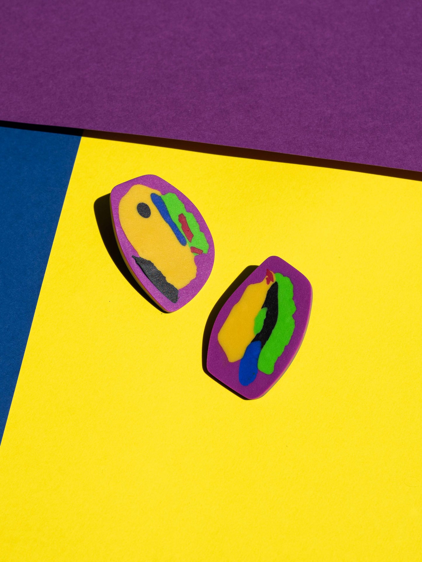 Front view of two original Salvaje studs, handmade in polymer clay, photographed on a colourful background under direct sunlight.