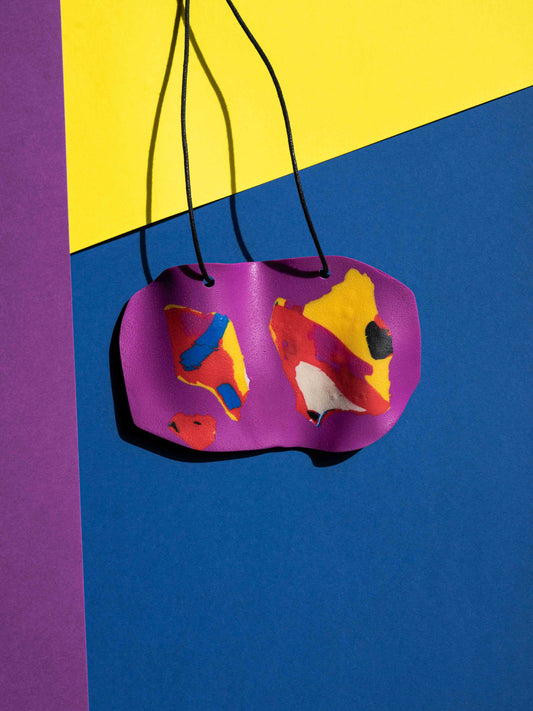 Front view of a salvaje pendant in magenta, yellow, red, blue and purple colours with strong lighting on a colourful background