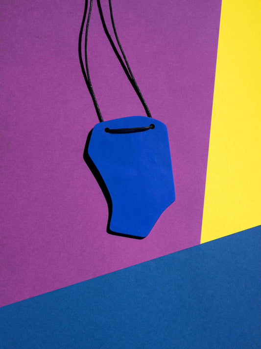 Backblue view of a salvaje pendant in green, magenta, yellow, blue, black and red colours with strong lighting on a colourful background