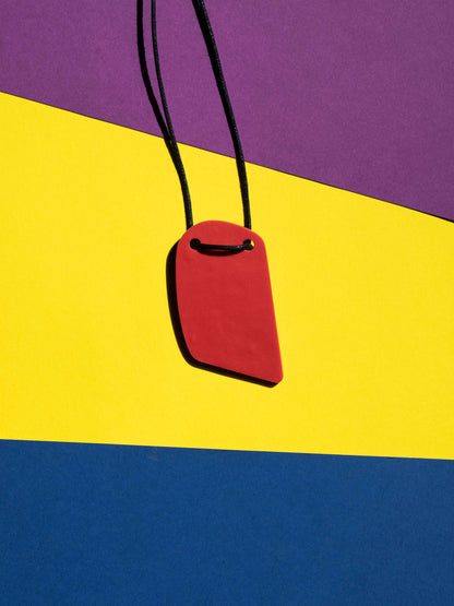 Back red view of a salvaje pendant in purple, magenta, yellow, blue, black and red colours with strong lighting on a colourful background