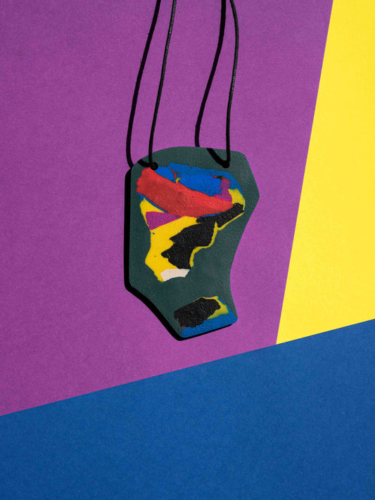 Front view of a salvaje pendant in green, magenta, yellow, blue, black and red colours with strong lighting on a colourful background