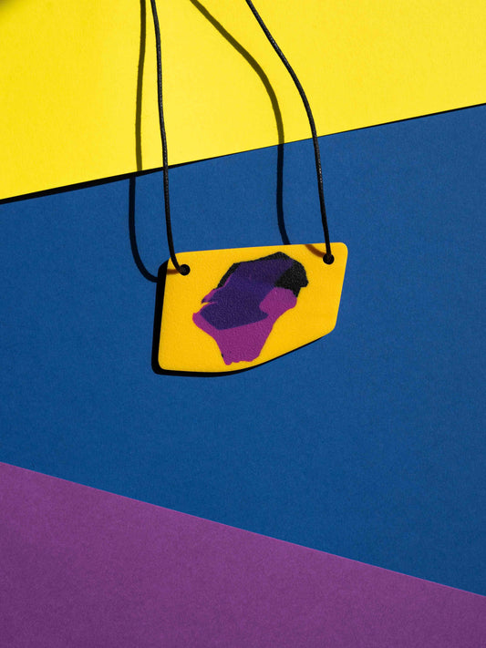 Front view of a salvaje pendant in magenta, yellow and purple colours with strong lighting on a colourful background