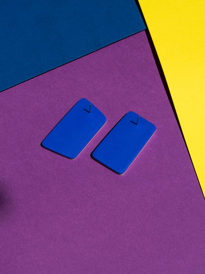 Back view of two original Salvaje studs, handmade in polymer clay, photographed on a colourful background under direct sunlight.