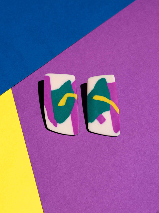 Front view of two original Salvaje studs, handmade in polymer clay, photographed on a colourful background under direct sunlight.