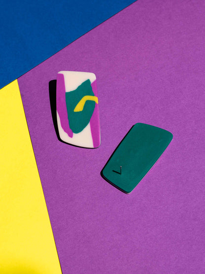 Front and back views of two original Salvaje studs, handmade in polymer clay, photographed on a colourful background under direct sunlight.